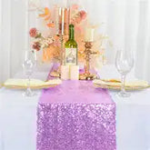 Elegant table setting with a sparkly purple sequin runner, wine glasses, and gold-rimmed plates.