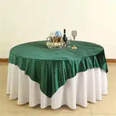 Round table covered with white tablecloth and emerald green overlay.