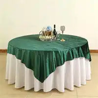 Round table covered with white tablecloth and emerald green overlay.