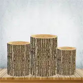 Three rustic tree trunk pedestals with smooth top surfaces and natural bark textures on the sides.